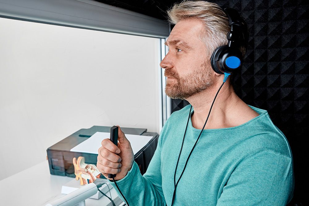 Patient seated in the sound-treated booth wearing audiometric headphones and holding the response button
